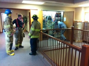 Firefighters discuss how to handle a leaky battery in Sitka's city hall on Monday morning. (KCAW photo by Ed Ronco)