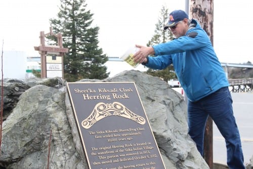 Andrew Roberts pours water on the Herring Rock, during a ceremony in Sitka Tuesday morning. (KCAW photo/Emily Forman)