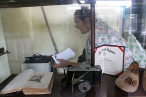 Karen Lucas goes through some boxes behind a display case inside the Port Alexander museum. Lucas runs the local historical society.