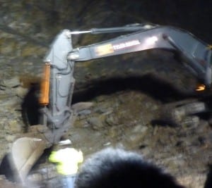 A construction worker watches as a backhoe digs into the area where blasting ruptured Sitka's main water line Wednesday.