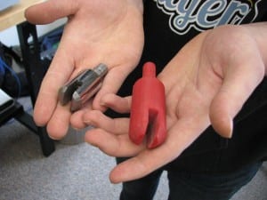 The red plastic bit was made in the 3D printer; the metal copy was made in the shop. (KCAW photo/Robert Woolsey)
