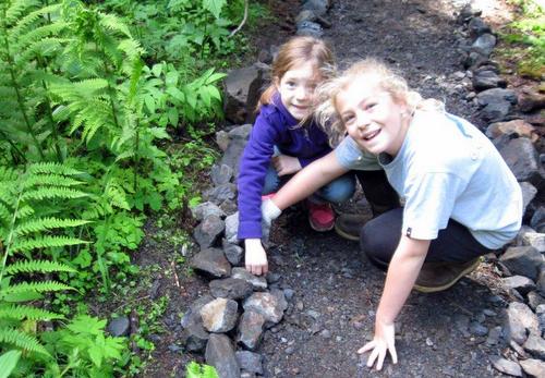 Cassidy Foster, 8, and Skyler Walk, 11, of Kodiak and Charlotte, NC, supplement the masonry on the upper Herring Cove trail. (Bill Foster photo)