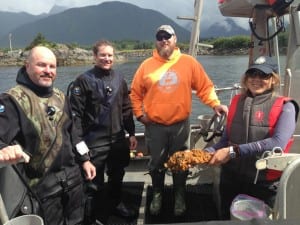 The staff of Dive Skiff 1 (from l to r) Jeff Meucci, Scott Forbes, Cody Jacobson, and Tammy Davis (holding a D.vex sample). The dive teams work test plots on both the rocky slopes of the Whiting causeway, and on its sandy bottom. (KCAW photo/Robert Woolsey)