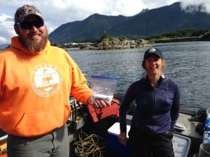 Tammy Davis (r) with fellow biologist Cody Jacobson prepare to send a half-pound of chlorine down to divers preparing the dome. (KCAW photo, Robert Woolsey)