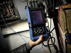 engineer Mike Gaffney uses a power quality analyzer to measure the energy use of the vessel's lighting. (Emily Russell/KCAW).